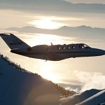 A Citation Jet cuts through the air above the mountains.