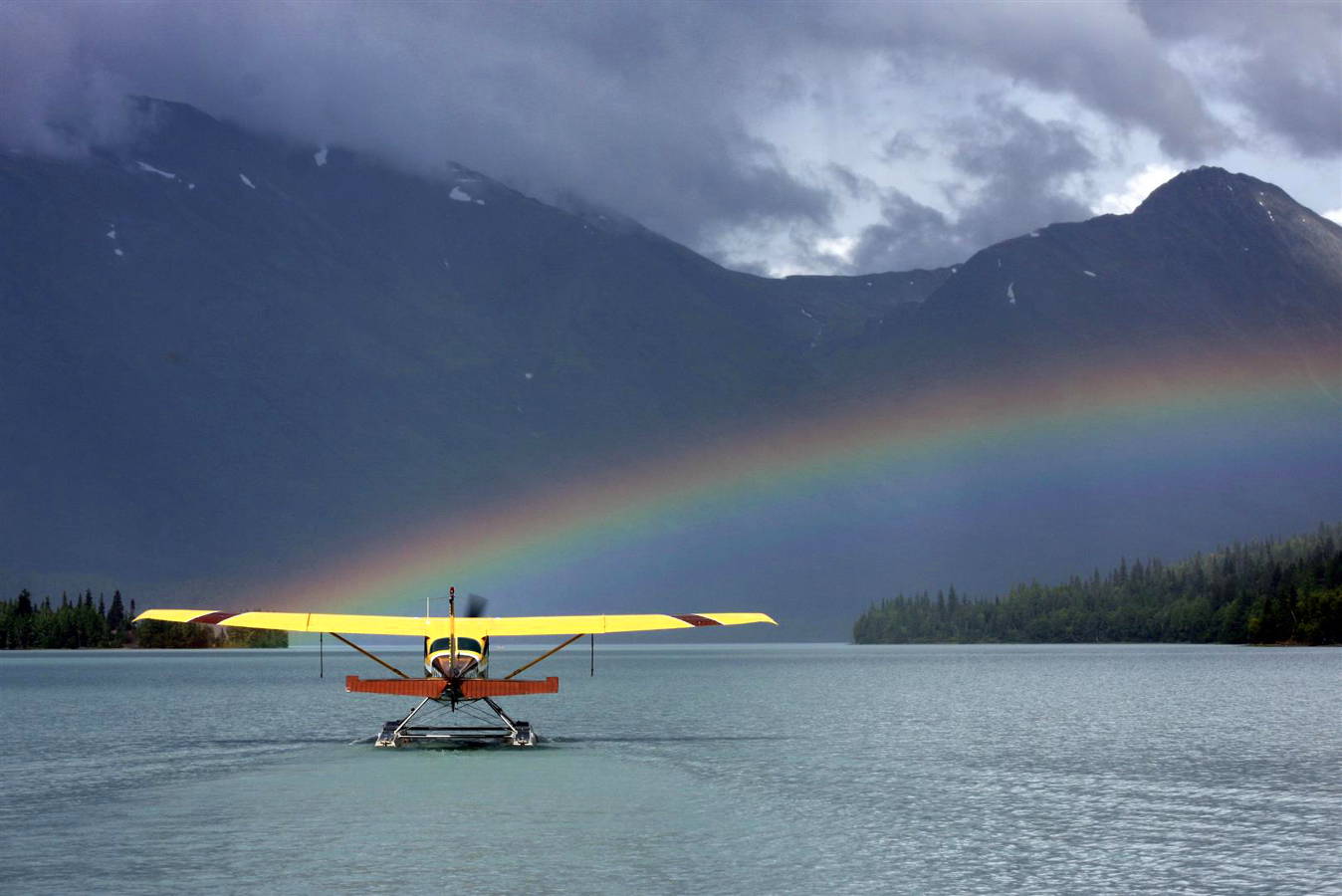 A seaplane on a beautiful Alaskan lake with a rainbow.