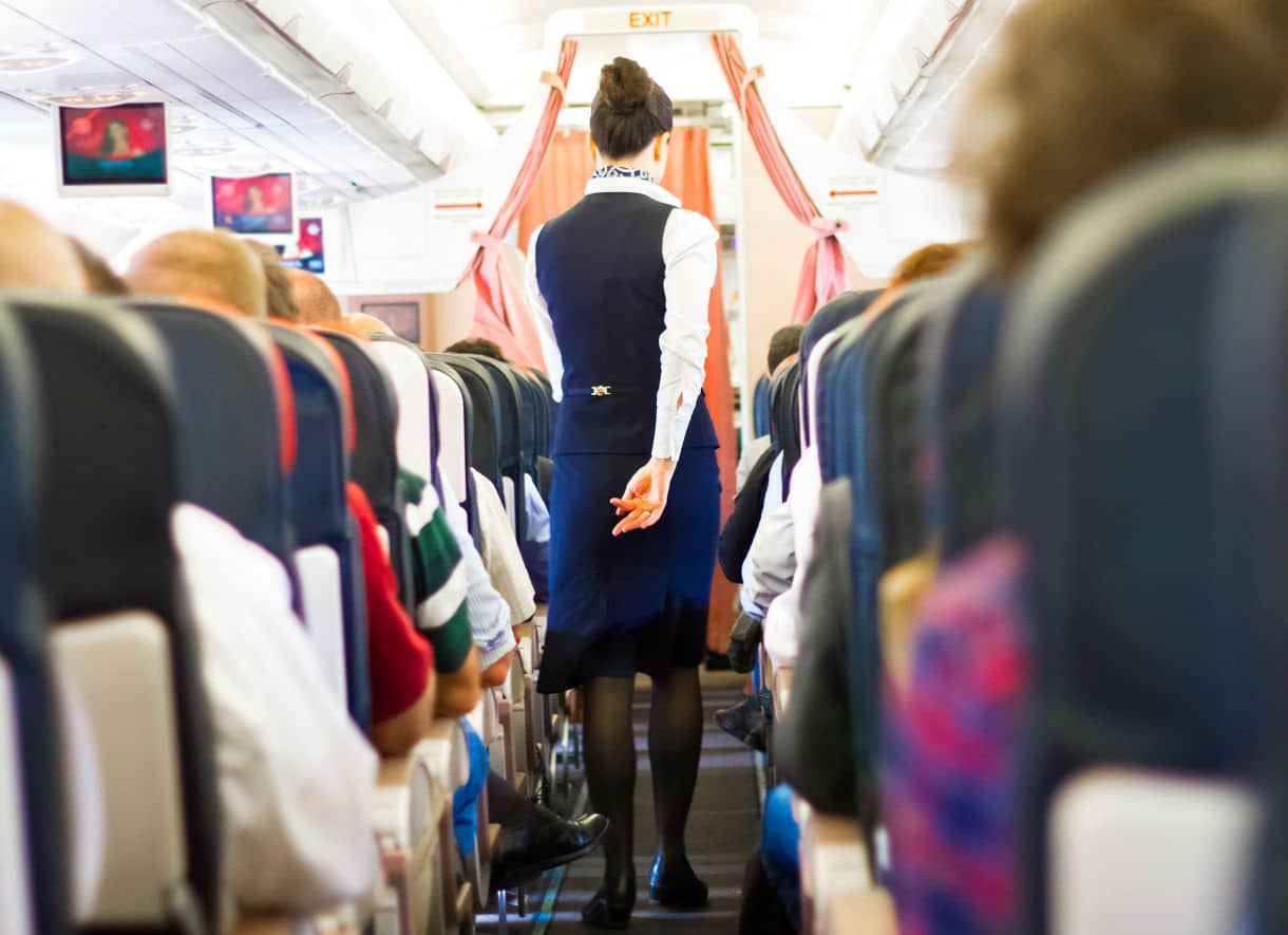 Flight attendant walking down the aisle of an airliner - Pilots and Flight Attendants