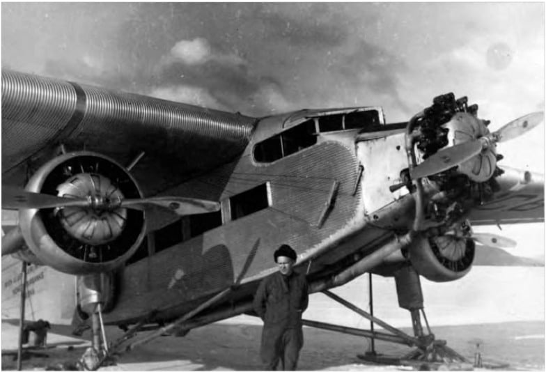 Noel Wien standing next to a Ford Trimotor plane.