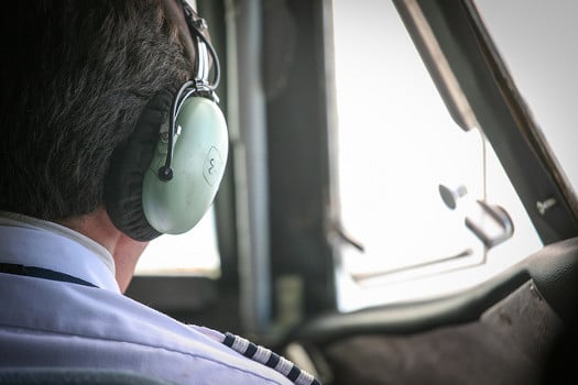 Airline pilot with a headset, in the cockpit - Are All Airline Pilot Training Schools the Same?