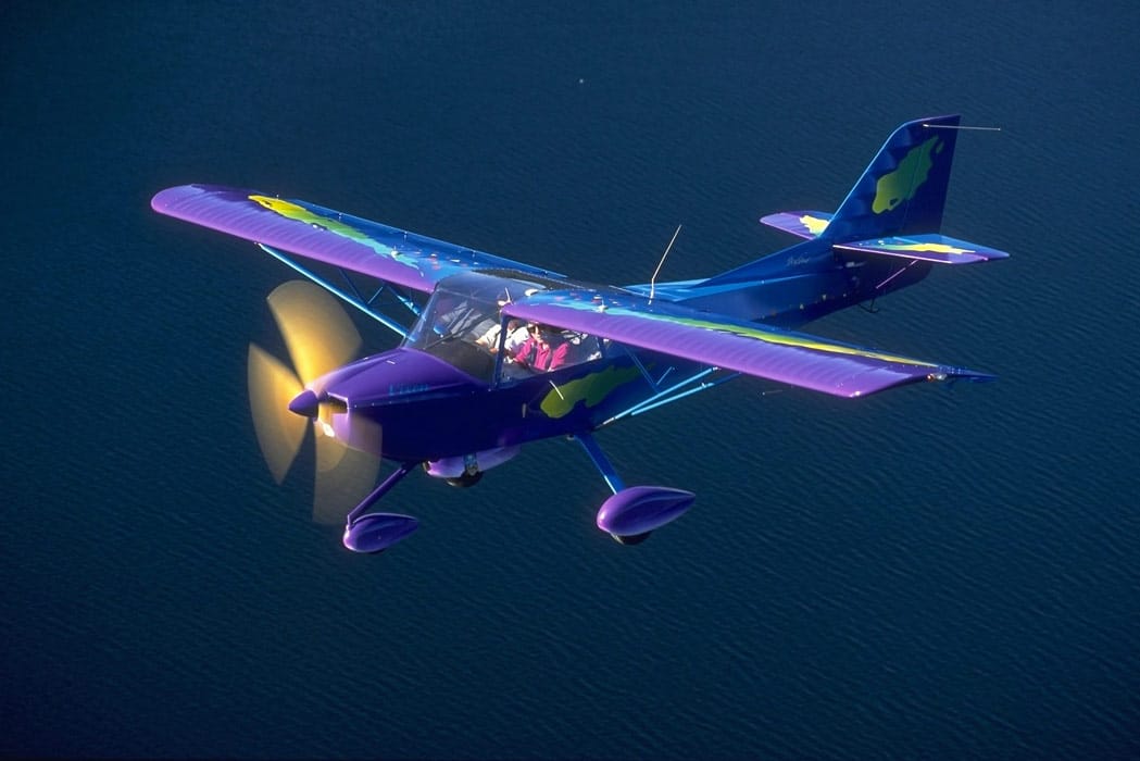 A Kitfox experimental aircraft flying over a lake