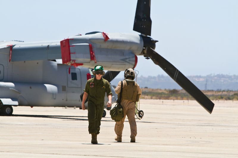 Military pilots with an Osprey aircraft in the backgorund