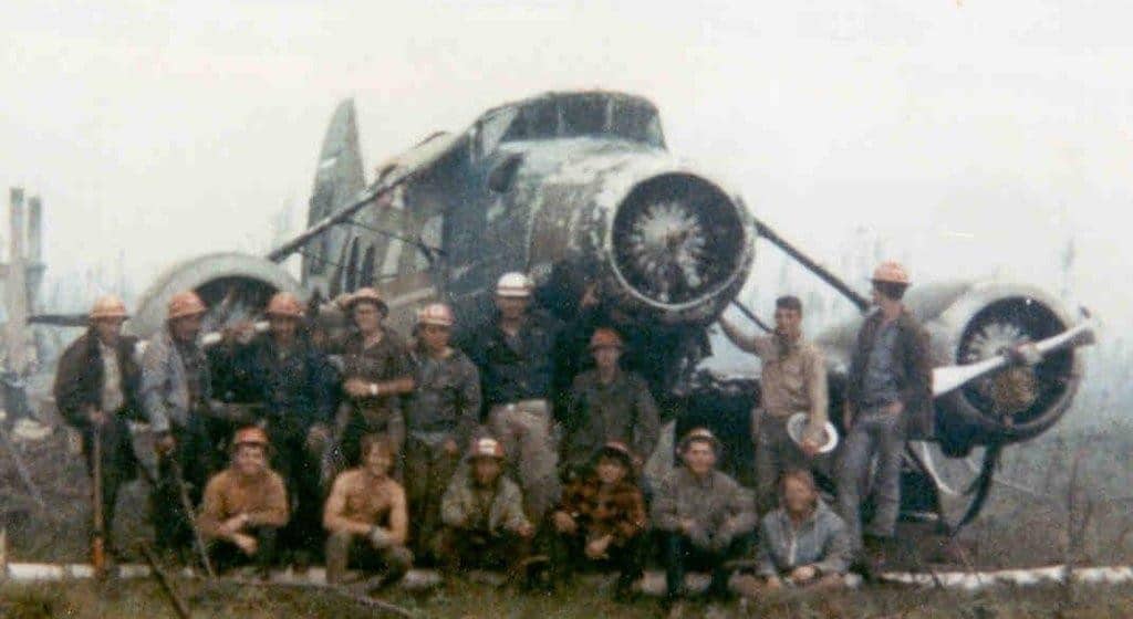 A group of fire fighters posing in front of a rescued Stinson Trimotor
