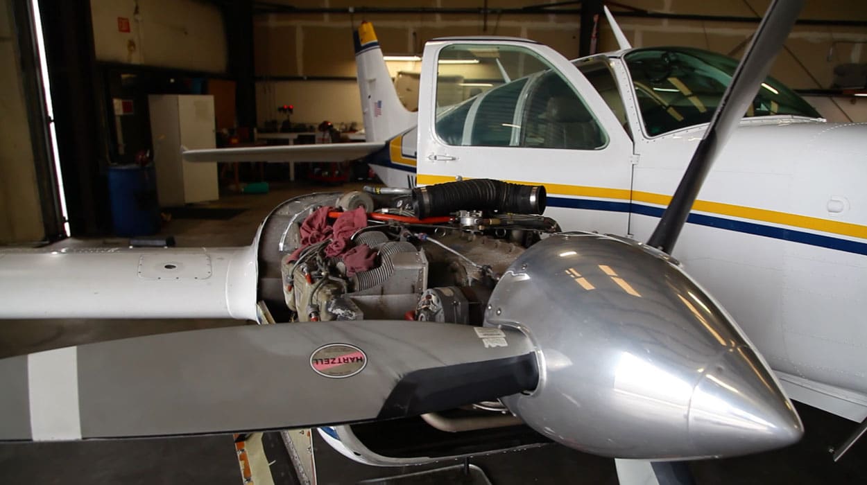 Twin engine aircraft being worked on by in an aviation mechanics shop