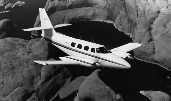 Cessna T303 Crusader in flight over redrock and water