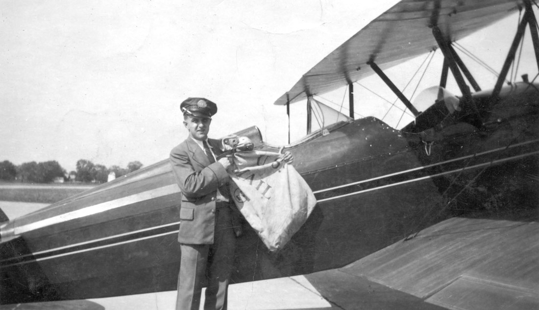 A pilot loading a plane with airmail, part of the history of airmail.