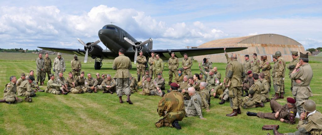 douglas dc-3 used in a d-day commemoration, surrounded by paratroops and soldiers