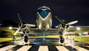 a douglas dc-3 at night on a wet runway