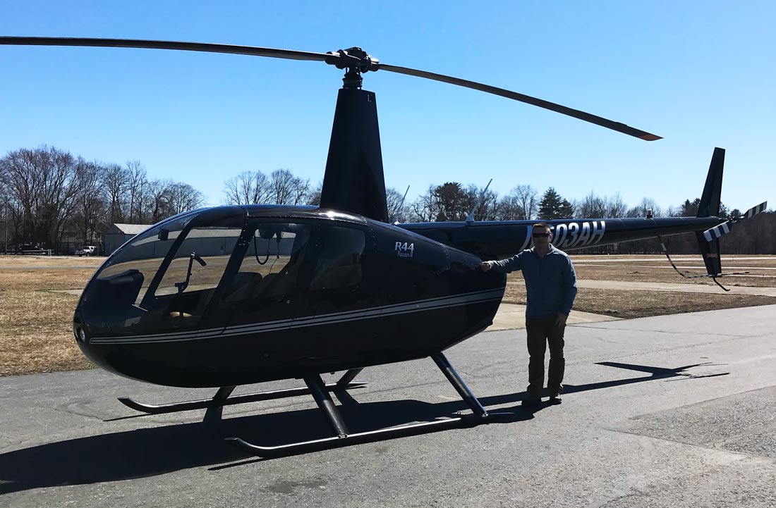 Pilot working on helicopter rating posing with Robinson R44