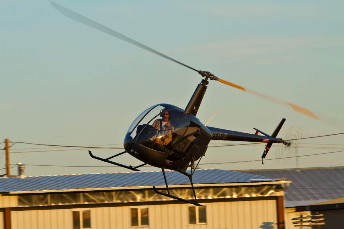 Pilot flying a helicopter around wires and electrical transmission towers.