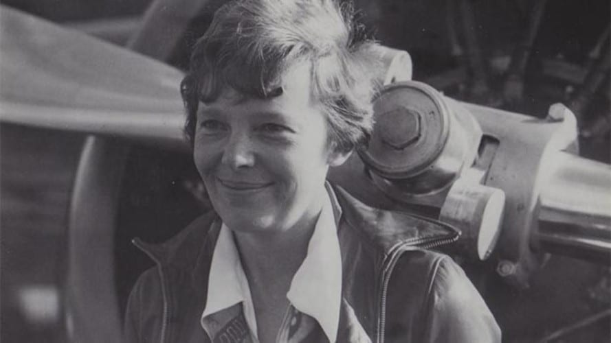 Amelia Earhart posing in front of an airplane