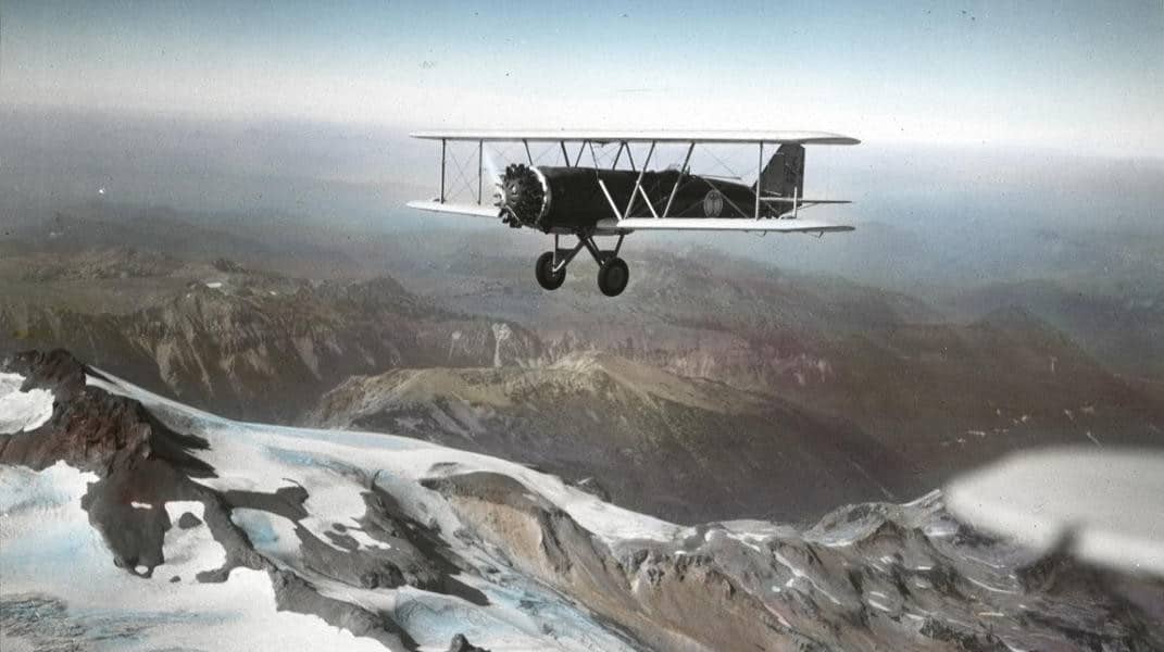 A Boeing Model 40A flying over a mountain range in the 1930s