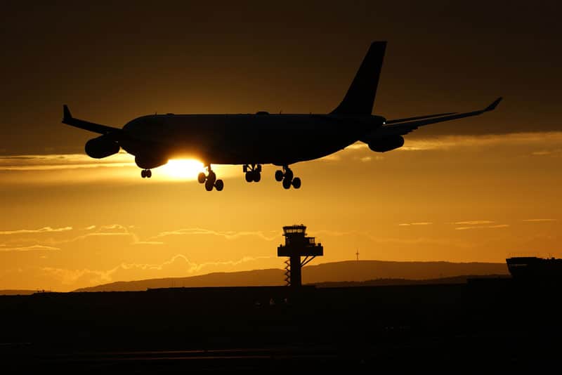 An airliner landing at sunset, with ATC tower in the background